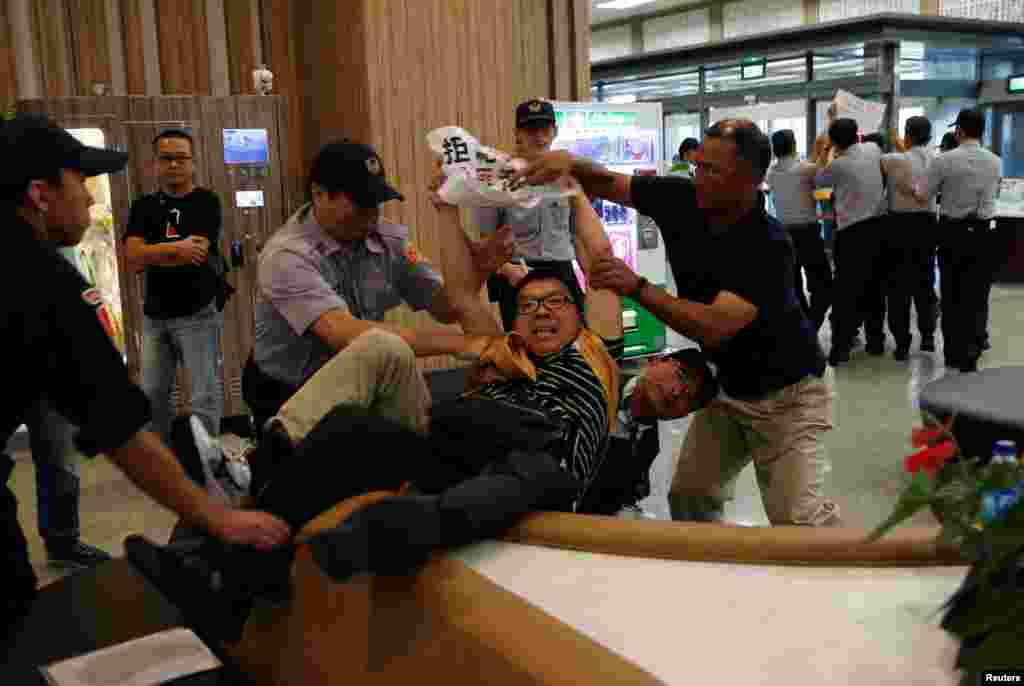 Polisi Taiwan menahan seorang demonstran anti-China saat pejabat komunis Shanghai tiba di bandara Songshan di Taipei, Taiwan.