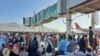 Les Afghans se pressent sur le tarmac de l'aéroport de Kaboul le 16 août 2021 pour fuir le pays alors que les talibans contrôlaient l'Afghanistan après que le président Ashraf Ghani eut fui le pays et reconnu que les insurgés avaient gagné la guerre de 20 ans.