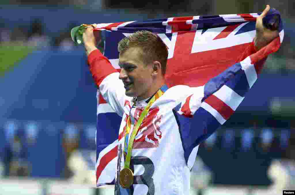 Perenang Inggris Adam Peaty berpose dengan bendera nasional setelah meraih medali emas. (Reuters/Michael Dalder) 