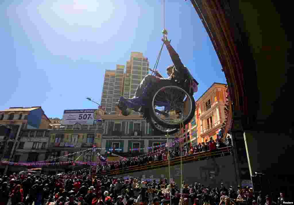 A woman with a physical disability is hoisted up a pedestrian bridge by fellow protesters during a rally demanding the government provide a monthly subsidy, in La Paz, Bolivia, May 3, 2016.