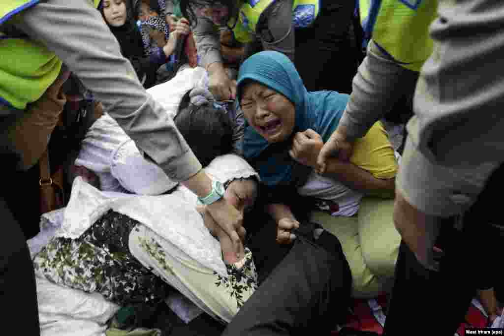 Indonesian Public Order Agency security officers pull up protesting residents from the road during the demolition of illegal houses at a slum area in Jakarta. According to media reports, more than 500 makeshift houses and permanent residences were demolished as the government plans to increase public spaces and tourist attractions in the area.