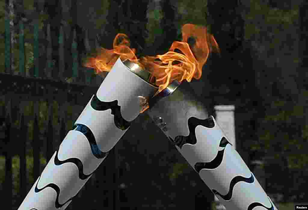 Olympic flame first torch bearer, Greek gymnast Eleftherios Petrounias (R) passes the torch to the second bearer, former volleyball player Giovane Gavio from Brazil, as they attend the Olympic flame lighting ceremony for the Rio 2016 Olympic Games on the site&nbsp;of ancient Olympia, Greece.
