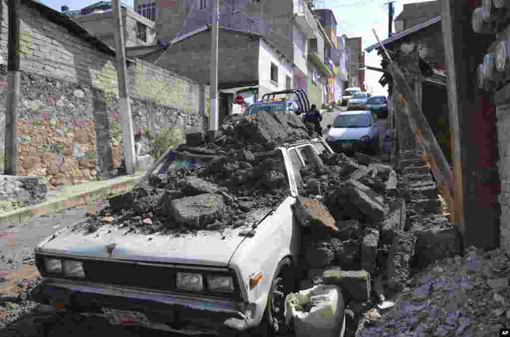 Sebuah mobil yang tengah diparkir mengalami kerusakan terkena reruntuhan dinding tembok setelah gempa besar mengguncang Chilpancingo, Meksiko. &nbsp;