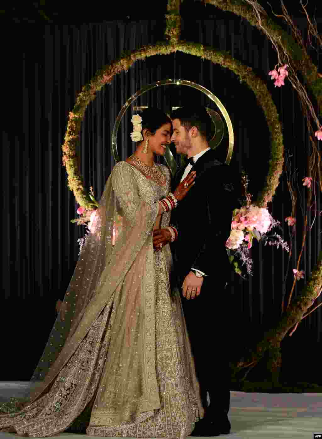 តួសម្តែងឥណ្ឌាអ្នកនាង Priyanka Chopra (ឆ្វេង) និងតារាចម្រៀងអាមេរិកលោក Nick Jonas ដែលទើបតែរៀបការថ្មីថ្មោងថតរូបក្នុងពិធីជប់លៀងក្នុងទីក្រុងញូវដែលីប្រទេសឥណ្ឌា។