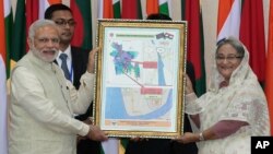 Bangladesh’s Prime Minister Sheikh Hasina, right, and Indian Prime Minister Narendra Modi hold a location map of Indian Economic Zones during an agreement program in Dhaka, Bangladesh, June 6, 2015.