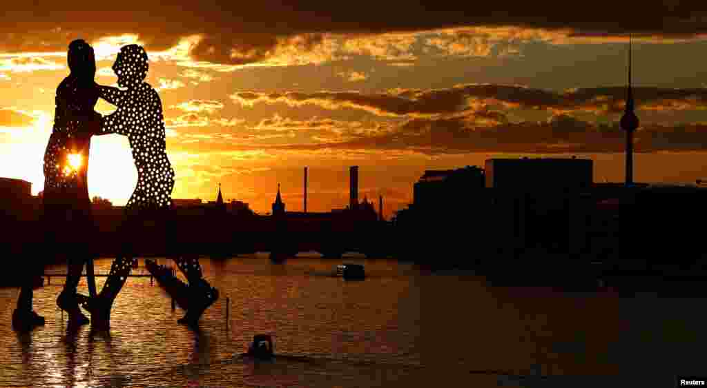Matahari terbenam di belakang patung &quot;Molecule Men&quot;, setinggi 30 meter karya Jonathan Borofsky, di Berlin, Jerman.