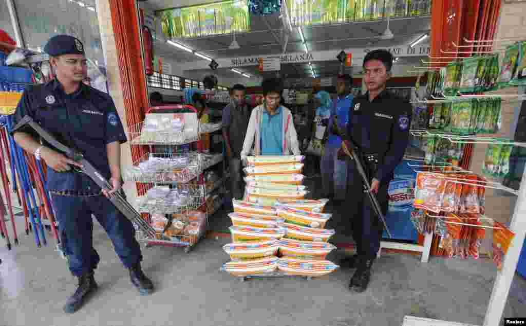 Polisi Malaysia mengawasi pengiriman barang ke toko kelontong di Felda Sahabat, dekat lokasi penyerbuan kamp kelompok bersenjata Filipina oleh pasukan Malaysia (6/3). (Reuters/Bazuki Muhammad)&nbsp;