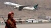 FILE - A Taliban fighter stands guard as a Pakistan International Airlines plane, the first commercial international flight to land after the Taliban retook power, takes off at the airport in Kabul on Sept. 13, 2021.
