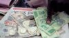 FILE - A man counts Zimbabwean dollar notes and coins and U.S. dollar notes on the streets of Harare, June 25, 2019. 