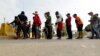 FILE - Migrants seeking asylum in the United States line up for a meal provided by volunteers near the international bridge in Matamoros, Mexico, April 30, 2019. 