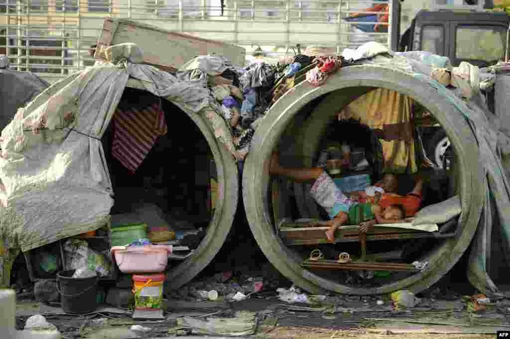 Families live in concrete pipes used as makeshift dwellings along a street in Manila, the Philippines.