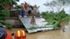 In this photo provided by the Philippine Coast Guard, residents stay on top of roofs to avoid floods while they wait to be rescued from floodwaters in Libon, Albay province, Philippines, Oct. 23, 2024. 