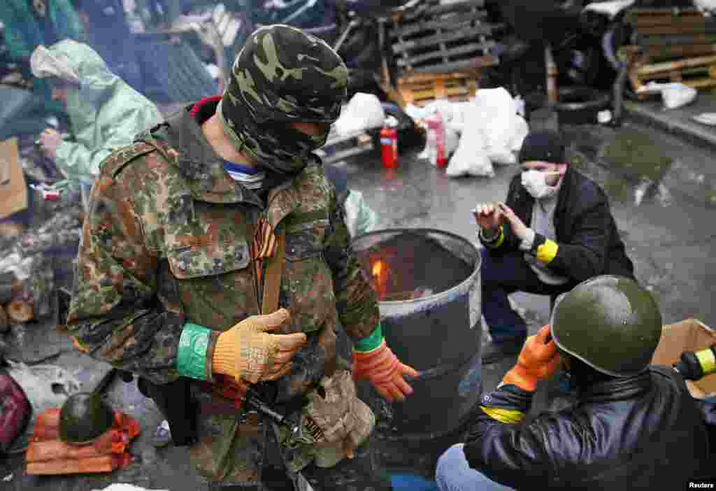 Pria-pria pro-Rusia menghangatkan diri dekat api di barikade dekat markas besar polisi di Slovyansk (13/4).&nbsp;(Reuters/Gleb Garanich)