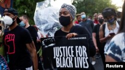 FILE - People participate in a demonstration on the first anniversary of the death of George Floyd, in Brooklyn, New York, May 25, 2021.