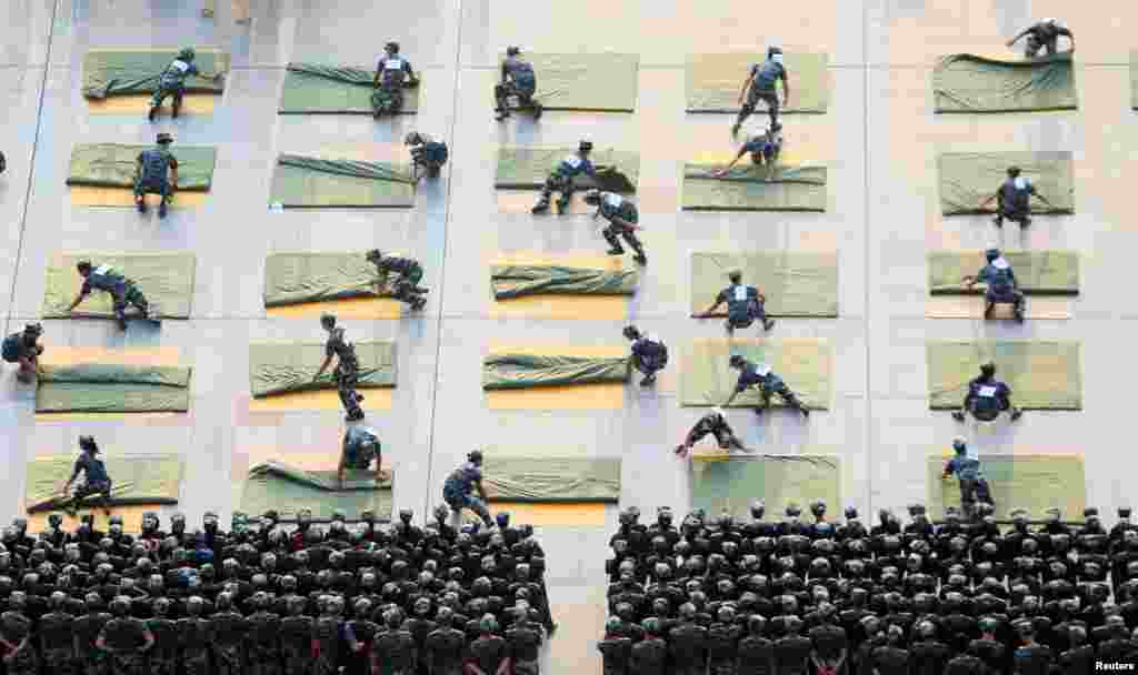 Para mahasiswa mengikuti lomba melipat selimut saat latihan militer untuk mahasiswa baru di Hengyang, Hunan, China.