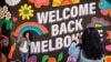 People take photos in front of a 'Welcome Back' sign after coronavirus disease restrictions were eased in Melbourne, Nov. 4, 2020.