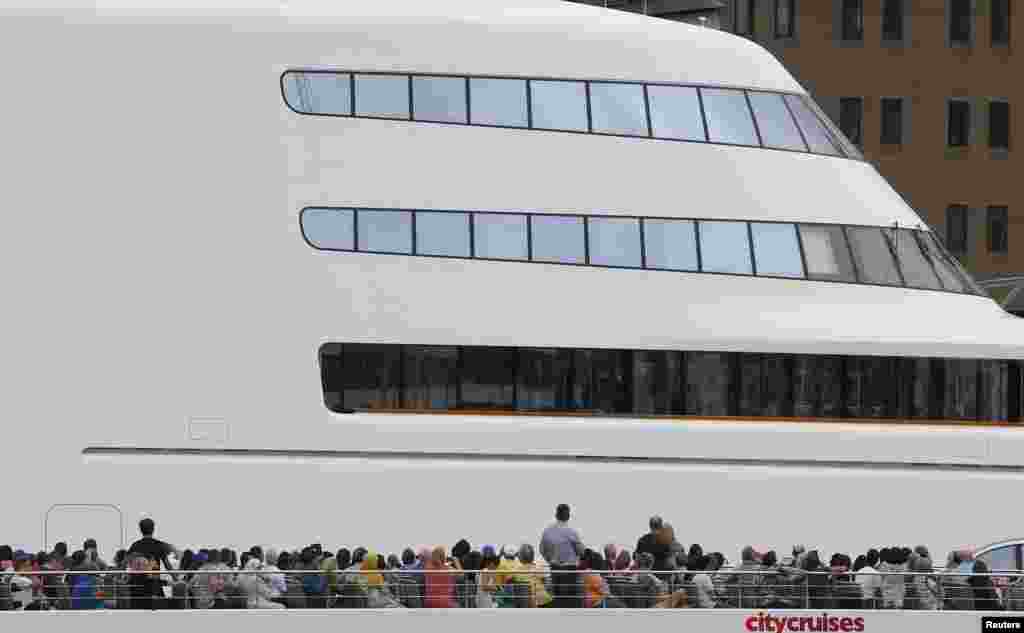 Para turis penumpang kapal cruise melewati superyacht milik konglomerat Rusia, Andrey Melnichenko, di sungai Thames, London.