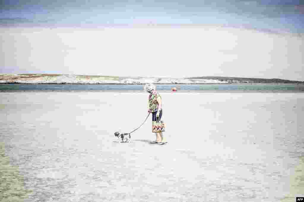 An elderly woman walks her dog in the empty Main Beach in Langebaan, South Africa.&nbsp;President Cyril Ramaphosa announced new lockdown measures to limit the spread of COVID-19.&nbsp;