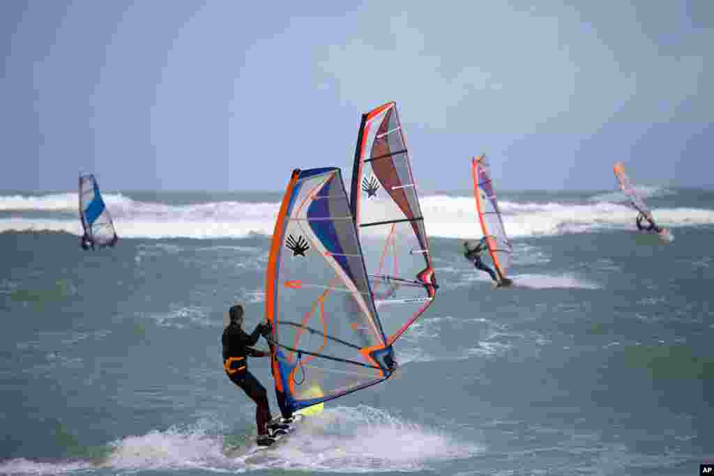 Wind surfers maneuver on the waves of the Mediterranean sea in Haifa, Israel.