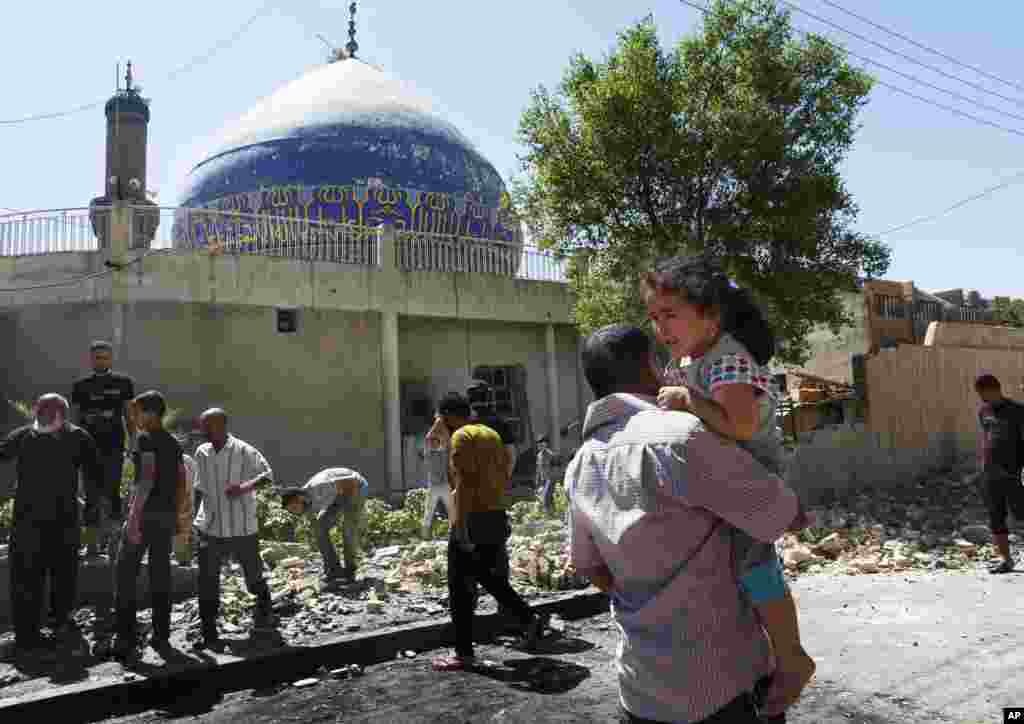People clean up after a car bomb attack hit a Shi&#39;ite mosque in Bayaa, Baghdad, July 29, 2013. 
