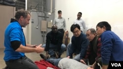 GJS trainer Shane Bell explains to VOA journalists how to move an unconscious patient. (Daphne Dung-Ning Fan/VOA) 