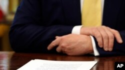 FILE - A document sits in front of President Donald Trump on his desk in the Oval Office of the White House in Washington, Oct. 11, 2019.