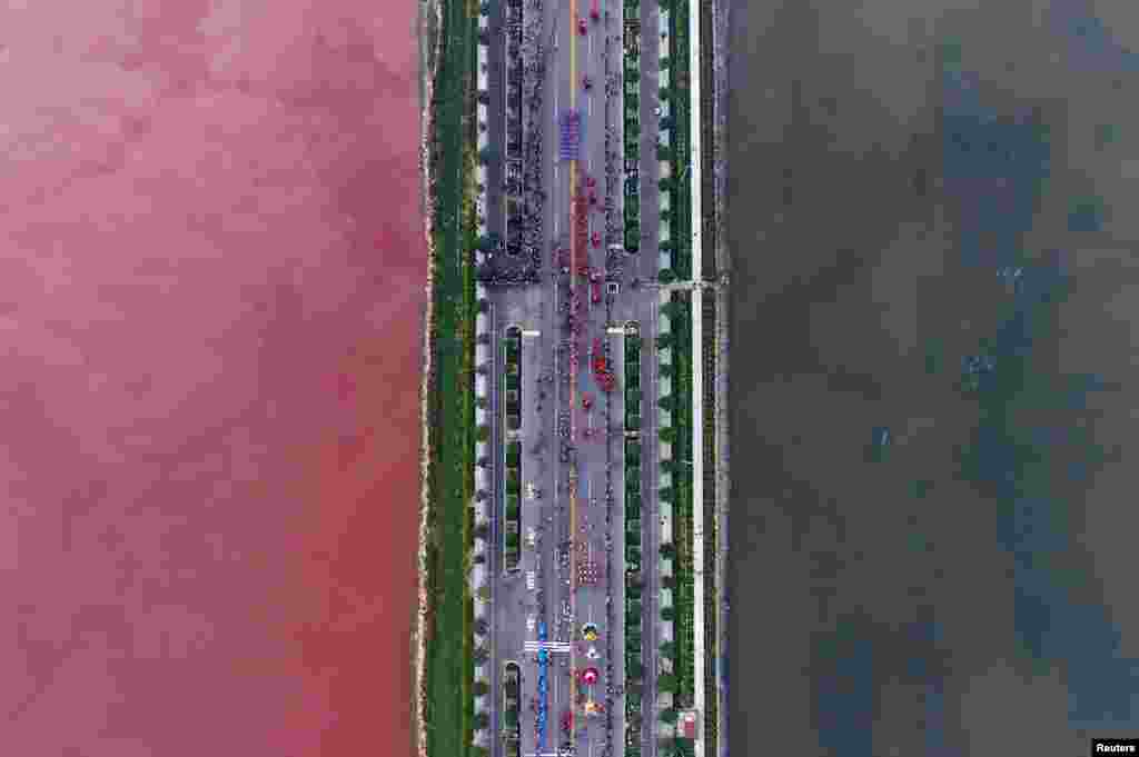 A salt lake which is separated by a road, shows parts of it in different colors due to algae, in Yuncheng, Shanxi Province, China.