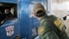 FILE - Border Patrol agent Eric Mendoza speaks to the driver of a tractor-trailer waiting to pass through the Laredo North vehicle checkpoint in Laredo, Texas, on Feb. 2, 2018. 