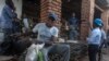 FILE - A vendor wears a face mask as a precaution against the coronavirus, as people around him do not, at the Lilongwe City market in Lilongwe, May 18, 2020. Malawi's government has vowed to crack down on COVID-19 prevention measures.