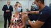 Australian Prime Minister Scott Morrison, left, watches as Sarah Fletcher receiving a vaccine at the Sydney local health district vaccination hub in Sydney, Feb. 19, 2021.