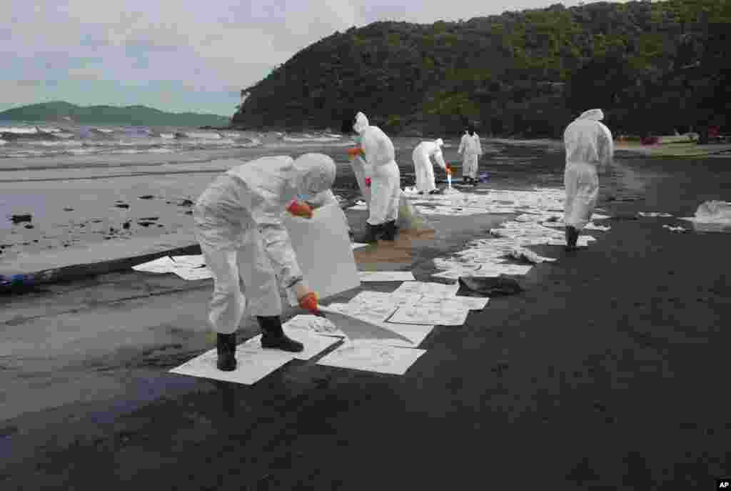 Para petugas membersihkan tumpahan minyak di pantai Teluk Prao, Pulau Samet di Thailand (29/7).