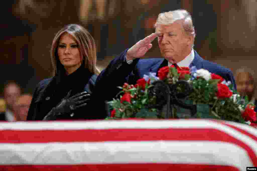 U.S. President Donald J. Trump, with first lady Melania Trump, salutes the casket containing the body of former President George H.W. Bush in the Rotunda of the U.S. Capitol in Washington, D.C., Dec. 3, 2018.