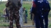 FILE - A migrant child looks at Hungarian policemen and soldier in Roszke, Hungary, Sept. 15, 2015. Hungarian police detained 16 people claiming to be Syrian and Afghan migrants for illegally crossing the Serbian border fence, a police spokeswoman said.