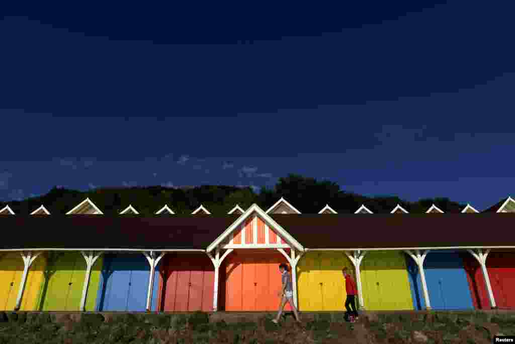 Dua remaja perempuan berjalan melewati rumah-rumah pantai di North Bay, Scarborough, Inggris Utara. Bangunan yang masuk dalam daftar Grade II (bangunan dengan kategori menarik) di North Bay itu diperkenalkan pada tahun 1911 dan masih digunakan hingga kini.