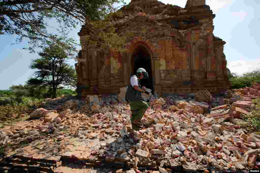 Seorang fotografer berjalan di luar sebuah pagoda yang hancur pasca gempa di kota Bagan, Myanmar.