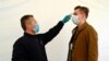 FILE PHOTO: An employee checks the temperature of another employee on arrival to work as PSA Peugeot re-opens after shutting down due to the coronavirus disease (COVID-19) outbreak in Trnava, Slovakia, Apr. 17, 2020. 