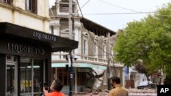 Emergency workers survey damage in Melbourne, Australia, where debris is scattered on a road after part of a wall fell from a building during an earthquake, Sept. 22, 2021.