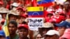FILE - A demonstrator holds a sign with a message that reads in Spanish: "Trump unblock Venezuela" as members of the Bolivarian militia attend a protest against U.S. sanctions on Venezuela, in Caracas, Venezuela, Aug. 7, 2019. 
