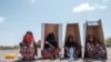 FILE - Women sit under UNHCR-branded cardboard boxes as they wait to be registered by the authorities at the compound of the Agda Hotel, in the city of Semera, Afar region, Ethiopia, Feb. 14, 2022.