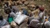 FILE - An elderly Ethiopian woman sits with others next to a sack of wheat donated to conflict victims in the town of Agula, in the Tigray region of northern Ethiopia, May 8, 2021.