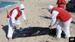 Libyan Red Crescent workers pick up a body of a drowned migrant near the city of Khoms, some 100 kilometers (60 miles) east of Tripoli, Libya, July 26, 2019.