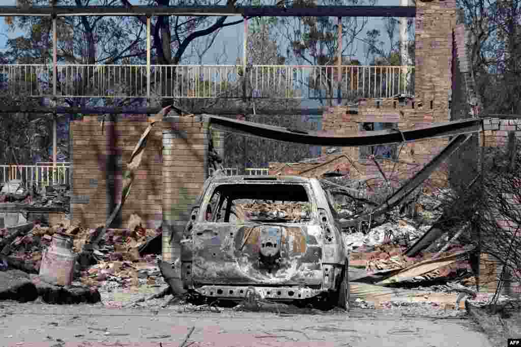 Sebuah mobil yang terbakar tampak di depan rumah yang rusak akibat kebakaran semak di Winmalee, Blue Mountains, Sydney. Kebakaran semak belukar itu melumpuhkan komunitas di sekitarnya  dan menghancurkan ratusan rumah di wilayah  Australia tenggara itu di mana di puluhan kebakaran masih belum bisa dikendalikan. 