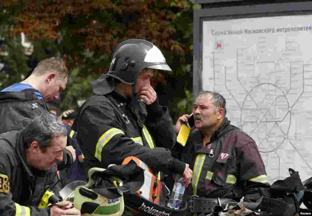 Members of emergency services stand near a map of metro train lines outside the station following an accident on the subway, in Moscow, July 15, 2014.