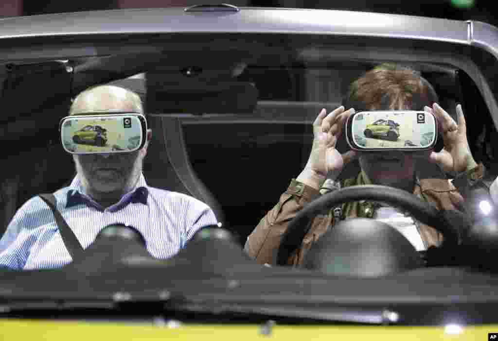 A woman touches a virtual reality 3D glasses as she and a man sit in a car prior to the shareholders&#39; meeting of the Daimler AG in Berlin, Germany.