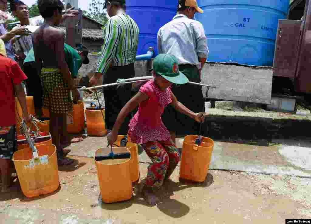 A child carries buckets of water as people wait to get drinking water from a donor's truck at a village of Dala township at outskirts of Yangon, Myanmar. Myanmar suffers from drought and drinking water shortages in at least 10 regions due to the El Nino weather phenomenon.