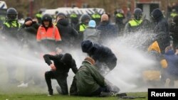 Polisi menyemprotkan meriam air untuk menghalau aksi protes di tengah restriksi untuk menanggulangi pandemi Covid-19 di Amsterdam, Belanda, 24 Januari 2021.
