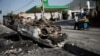 A man pulls a cart as he walks past a burned car on a street of Port-au-Prince, Haiti, July 8, 2018. 