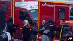 在警察冲进巴黎一家被劫持的犹太超市后，一名保安人员把被解救的人质引向安全地点。（2015年1月9日）