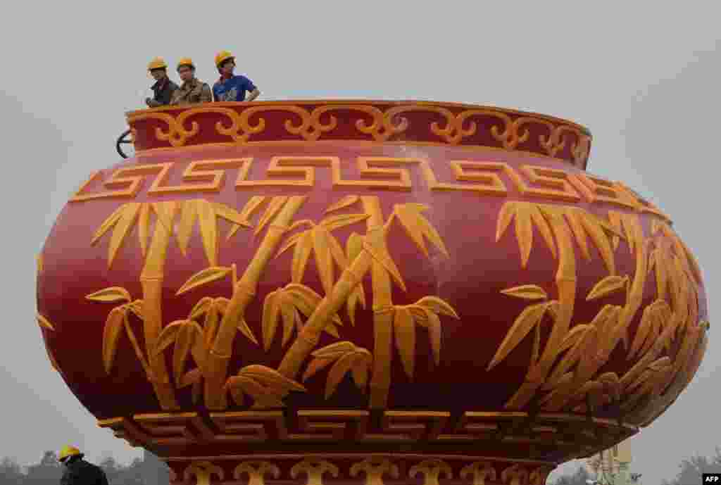 Workers install a giant vase as part of the upcoming Chinese National Day celebrations at Tiananmen Square in Beijing, China.