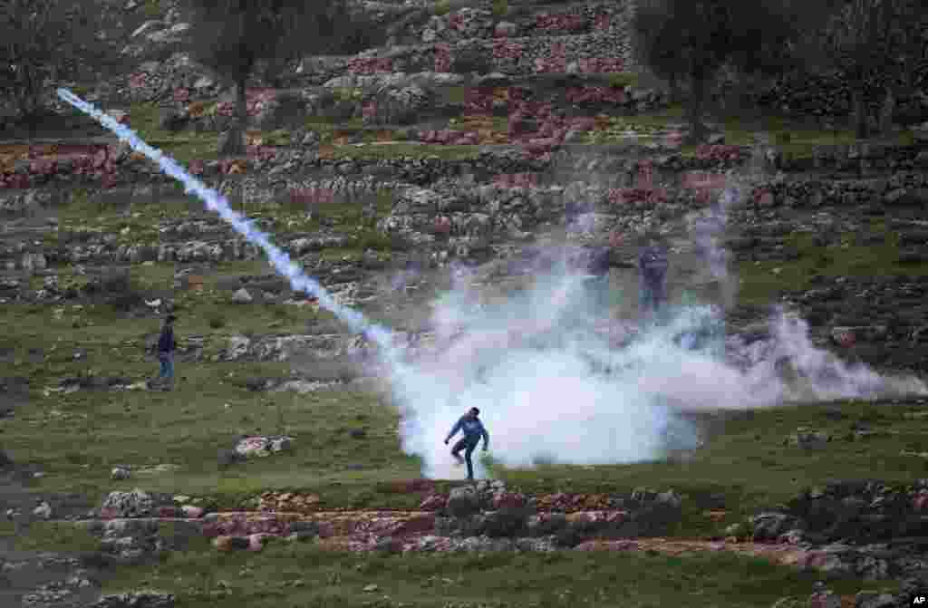 A Palestinian demonstrator throws back a tear gas canister that was fired by Israeli troops during a demonstration, calling for the release of Palestinian journalist Mohammed al-Qeq, outside the Ofer military prison near the West Bank city of Ramallah.